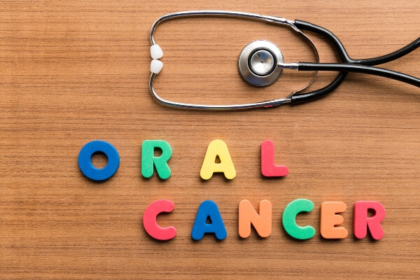 The words oral cancer are spelled out on a desk sitting next to a stethoscope.