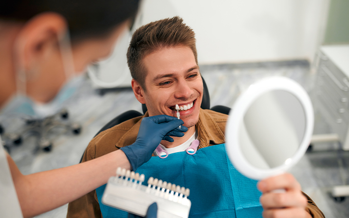 Dentist comparing a dental veneer to a patient's teeth