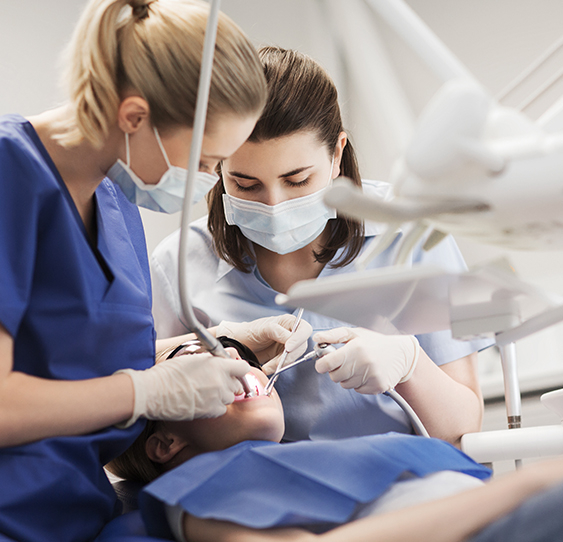 Dentist and her assistant treating a patient's teeth