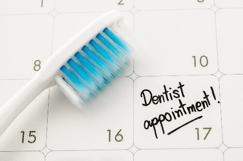 A dental appointment is set on a calendar with a toothbrush laid on top.