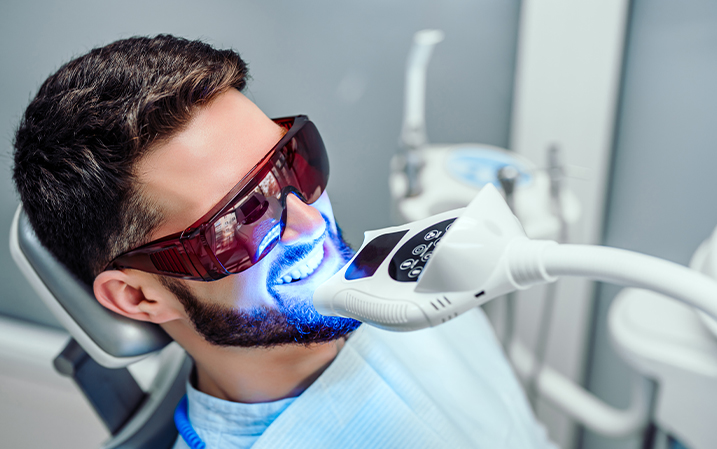 Dentist using light therapy to whiten a patient's teeth